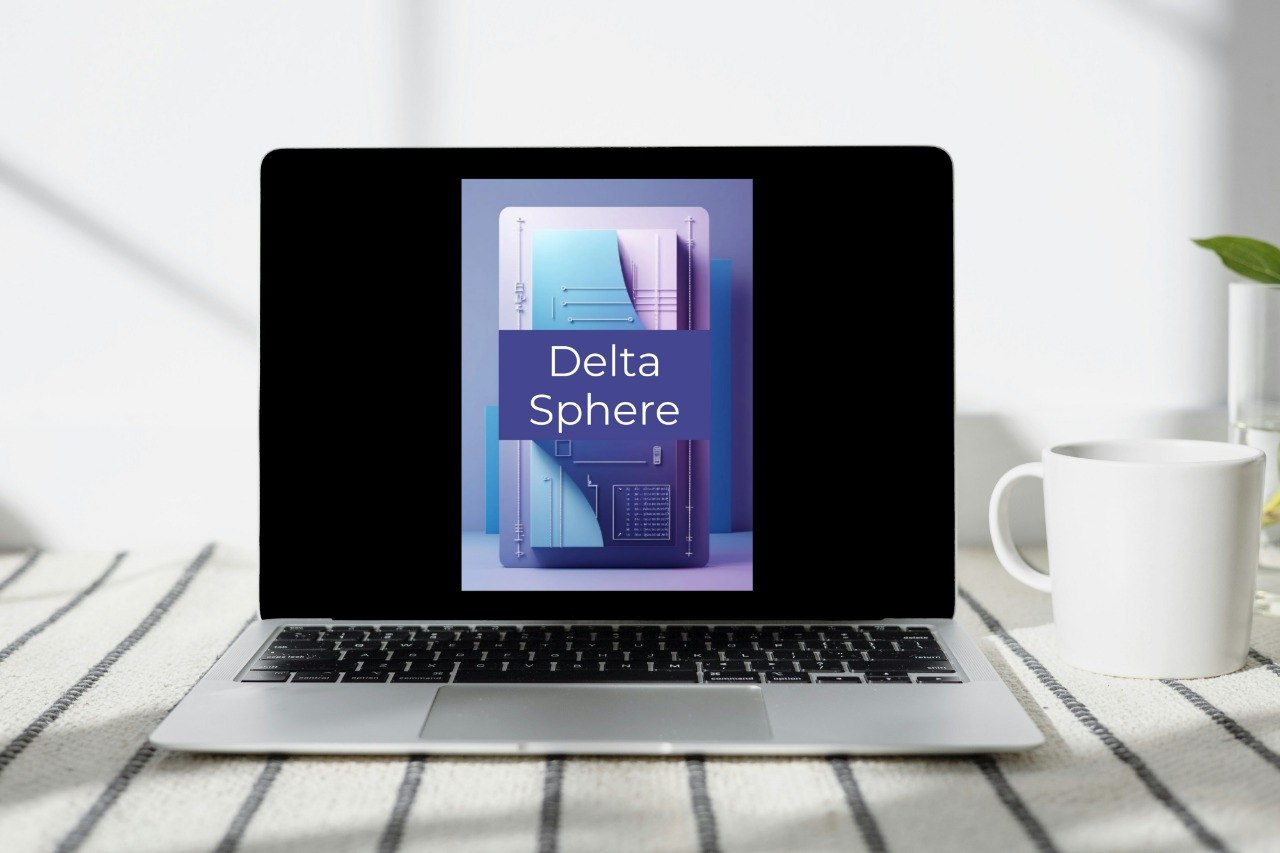 A silver laptop sits open on a striped fabric surface, displaying a book or cover titled 'Delta Sphere' on its screen. A white mug is to the right, and the background is a bright, softly lit indoor setting.
