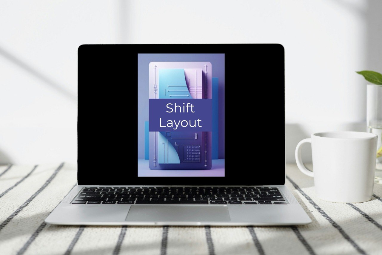 A silver laptop sits on a striped fabric surface next to a white mug, with a screen displaying a purple and blue graphic that reads 'Shift Layout'.